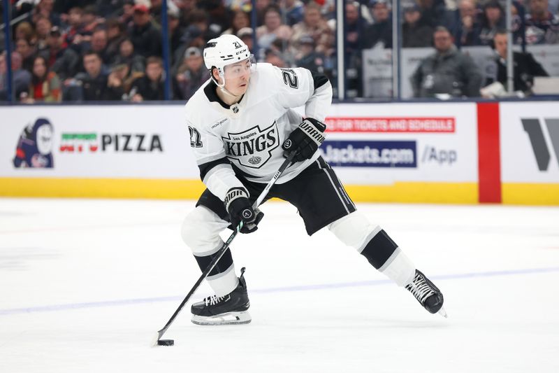 Jan 25, 2025; Columbus, Ohio, USA;  Los Angeles Kings defenseman Jordan Spence (21) controls the puck during the third period against the Columbus Blue Jackets at Nationwide Arena. Mandatory Credit: Joseph Maiorana-Imagn Images