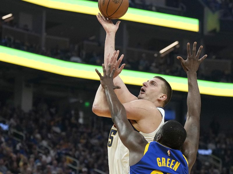 SAN FRANCISCO, CALIFORNIA - FEBRUARY 25: Nikola Jokic #15 of the Denver Nuggets shoot over Draymond Green #23 of the Golden State Warriors in the first quarter of an NBA basketball game at Chase Center on February 25, 2024 in San Francisco, California. NOTE TO USER: User expressly acknowledges and agrees that, by downloading and or using this photograph, User is consenting to the terms and conditions of the Getty Images License Agreement. (Photo by Thearon W. Henderson/Getty Images)