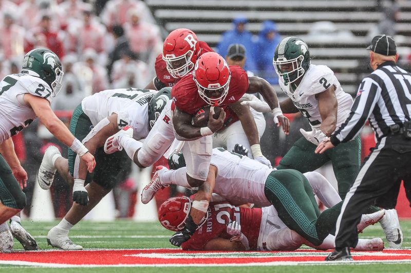 Oct 14, 2023; Piscataway, New Jersey, USA; Rutgers Scarlet Knights running back Kyle Monangai (5) fights for yards as Michigan State Spartans linebacker Jacoby Windmon (4) and defensive lineman Khris Bogle (2) pursue during the second half at SHI Stadium. Mandatory Credit: Vincent Carchietta-USA TODAY Sports