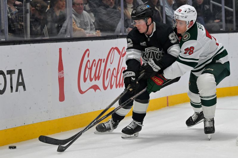 Jan 5, 2026; Los Angeles, California, USA; Los Angeles Kings defenseman Brandt Clarke (92) and Minnesota Wild center Nico Sturm (78) battle for the puck in the first period at Crypto.com Arena. Mandatory Credit: Jayne Kamin-Oncea-Imagn Images
