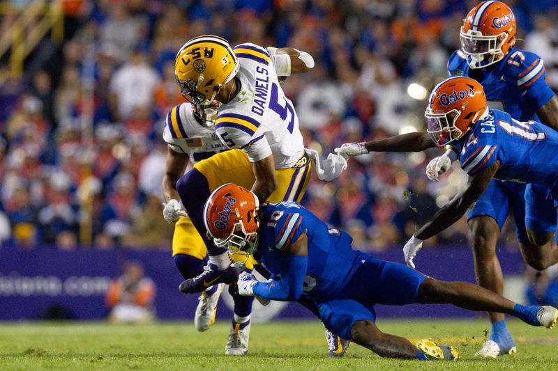 Nov 11, 2023; Baton Rouge, Louisiana, USA;  LSU Tigers quarterback Jayden Daniels (5) is tackled by Florida Gators safety Miguel Mitchell (10) during the second half at Tiger Stadium. Mandatory Credit: Stephen Lew-USA TODAY Sports