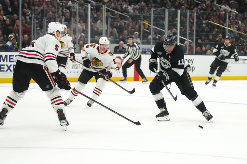 Nov 2, 2024; Los Angeles, California, USA; LA Kings center Anze Kopitar (11) skates with the puck against Chicago Blackhawks defenseman Connor Murphy (5) and center Ryan Donato (8) in the second period at Crypto.com Arena. Mandatory Credit: Kirby Lee-Imagn Images