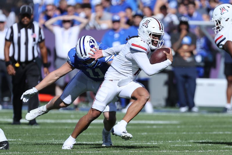 Oct 12, 2024; Provo, Utah, USA; Arizona Wildcats quarterback Noah Fifita (11) runs from Brigham Young Cougars linebacker Harrison Taggart (11) during the second quarter at LaVell Edwards Stadium. Mandatory Credit: Rob Gray-Imagn Images