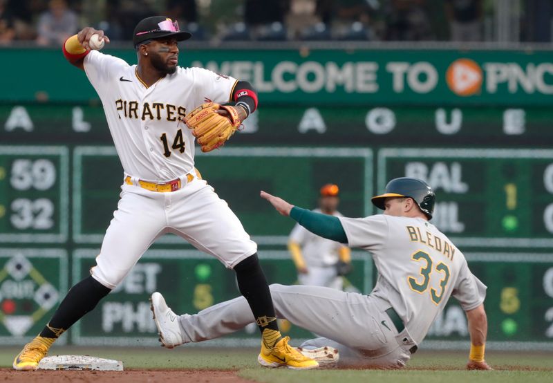 Jun 6, 2023; Pittsburgh, Pennsylvania, USA;  Pittsburgh Pirates shortstop Rodolfo Castro (14) turns a double play over Oakland Athletics left fielder JJ Bleday (33) during the third inning at PNC Park. Mandatory Credit: Charles LeClaire-USA TODAY Sports