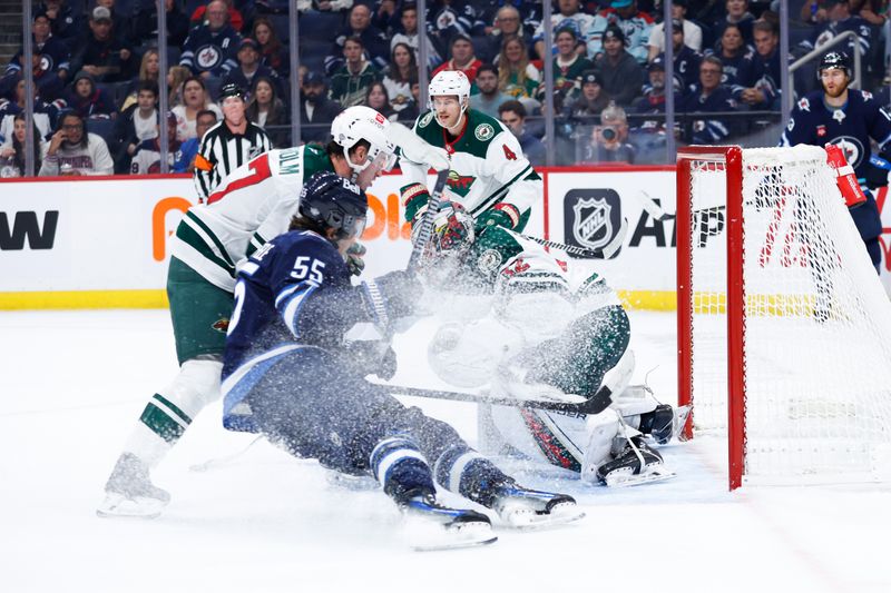 Oct 13, 2024; Winnipeg, Manitoba, CAN;  Winnipeg Jets forward Mark Scheifele (55) slides into Minnesota Wild goalie Filip Gustavsson (32)  during the second period at Canada Life Centre. Mandatory Credit: Terrence Lee-Imagn Images