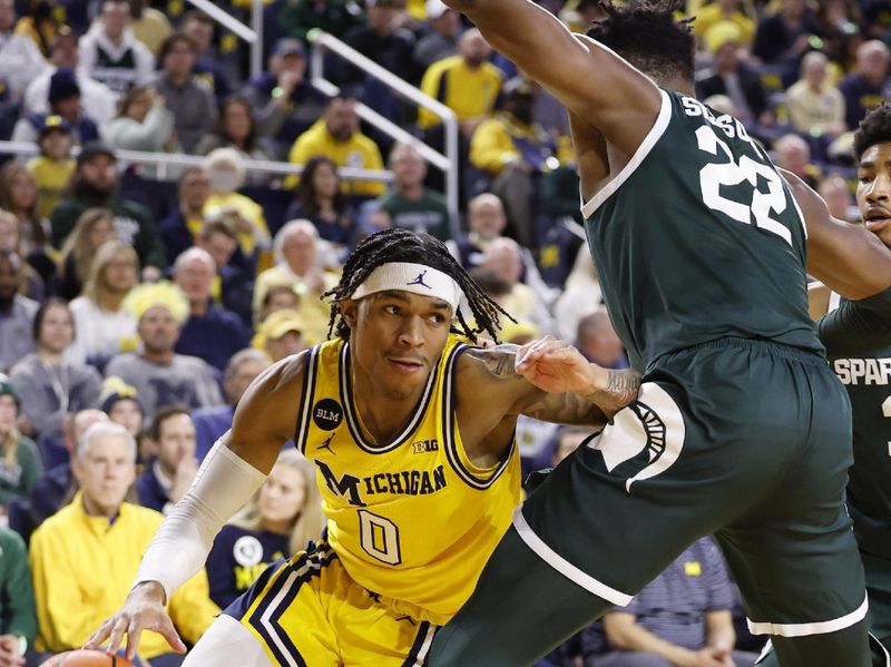 Feb 18, 2023; Ann Arbor, Michigan, USA;  Michigan Wolverines guard Dug McDaniel (0) dribbles the ball against Michigan State Spartans center Mady Sissoko (22) in the first half at Crisler Center. Mandatory Credit: Rick Osentoski-USA TODAY Sports