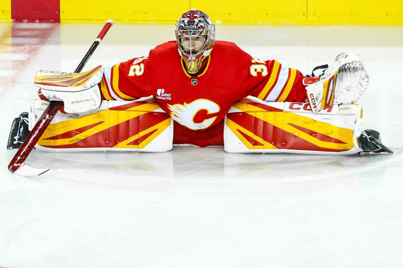 Oct 3, 2025; Calgary, Alberta, CAN; Calgary Flames goaltender Dustin Wolf (32) stretches during the warmup period against the Winnipeg Jets at Scotiabank Saddledome. Mandatory Credit: Sergei Belski-Imagn Images