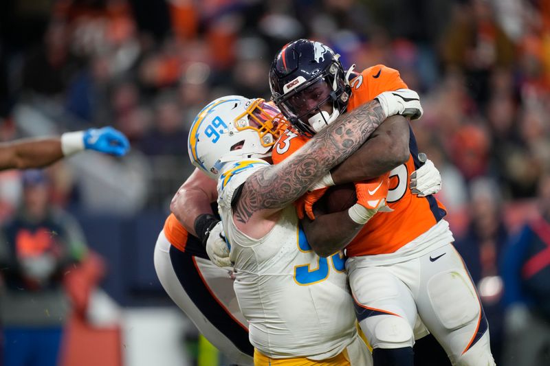 Los Angeles Chargers defensive tackle Scott Matlock (99) wraps up Denver Broncos running back Javonte Williams (33) in the second half of an NFL football game in Empower Field at Mile High Sunday, Dec. 31, 2023, in Denver. (AP Photo/David Zalubowski)