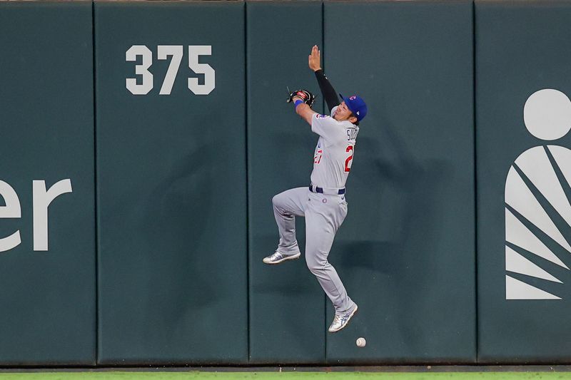 Sep 28, 2023; Atlanta, Georgia, USA; Chicago Cubs right fielder Seiya Suzuki (27) reaches for a fly ball against the Atlanta Braves in the third inning at Truist Park. Mandatory Credit: Brett Davis-USA TODAY Sports