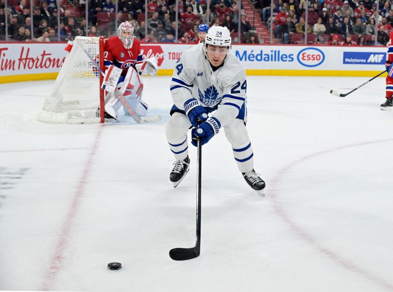 Apr 6, 2024; Montreal, Quebec, CAN; Toronto Maple Leafs forward Connor Dewar (24) plays the puck next to Montreal Canadiens goalie Cayden Primeau (30) during the third period at the Bell Centre. Mandatory Credit: Eric Bolte-USA TODAY Sports