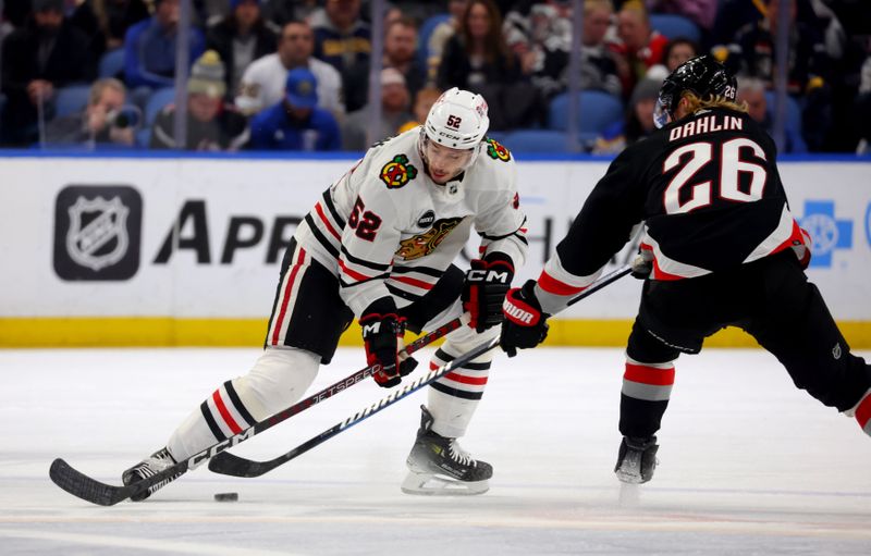 Jan 18, 2024; Buffalo, New York, USA;  Chicago Blackhawks center Reese Johnson (52) tries to block a pass by Buffalo Sabres defenseman Rasmus Dahlin (26) during the third period at KeyBank Center. Mandatory Credit: Timothy T. Ludwig-USA TODAY Sports