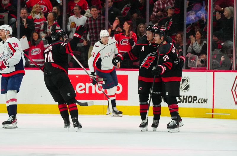 Apr 5, 2024; Raleigh, North Carolina, USA; Carolina Hurricanes center Jake Guentzel (59) is congratulated after his goal by center Sebastian Aho (20) and center Seth Jarvis (24) against the Washington Capitals during the second period at PNC Arena. Mandatory Credit: James Guillory-USA TODAY Sports