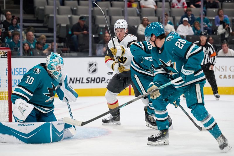 Sep 26, 2025; San Jose, California, USA; Vegas Golden Knights left wing Cole Reinhardt (23) vies for a loose puck in the air against San Jose Sharks goaltender Yaroslav Askarov (30), defenseman Jack Thompson (26) and defenseman Mario Ferraro (38) during the first period at SAP Center at San Jose. Mandatory Credit: Robert Edwards-Imagn Images