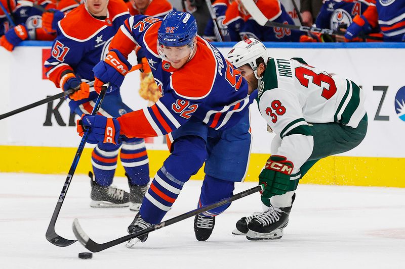 Nov 21, 2024; Edmonton, Alberta, CAN; Edmonton Oilers forward Vasily Podkolzin (92) carries the puck around Minnesota Wild forward Ryan Hartman (38) during the third period at Rogers Place. Mandatory Credit: Perry Nelson-Imagn Images