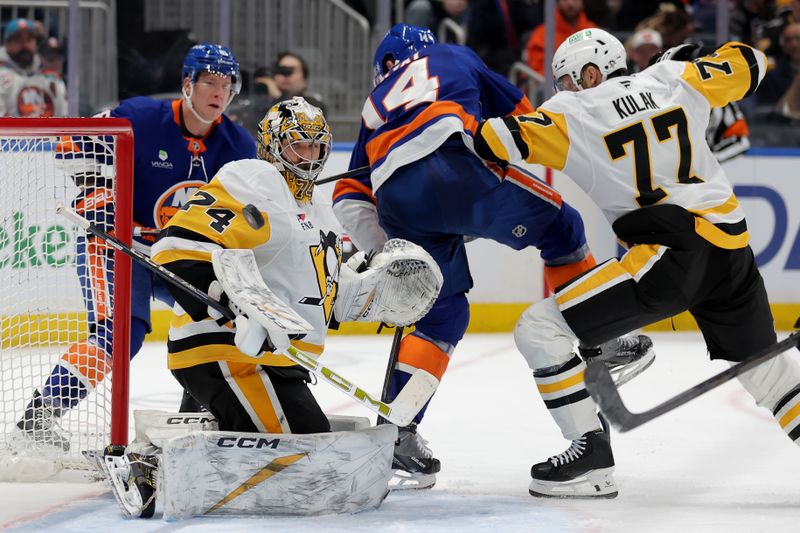 Feb 3, 2026; Elmont, New York, USA; Pittsburgh Penguins goaltender Stuart Skinner (74) makes a save in front of New York Islanders center Bo Horvat (14) and Penguins defenseman Brett Kulak (77) during the second period at UBS Arena. Mandatory Credit: Brad Penner-Imagn Images