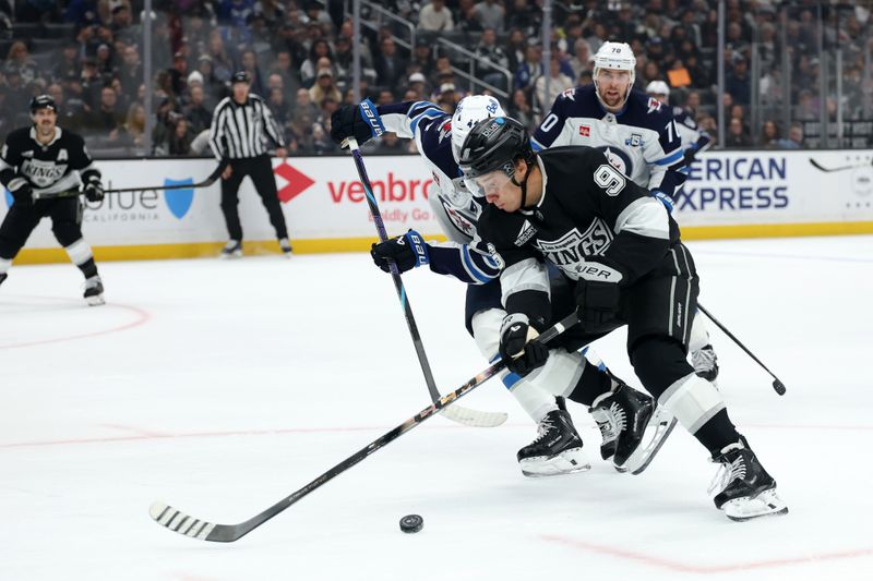 Nov 4, 2025; Los Angeles, California, USA;  Los Angeles Kings left wing Andrei Kuzmenko (96) fights for the puck against Winnipeg Jets defenseman Josh Morrissey (44) during the second period at Crypto.com Arena. Mandatory Credit: Kiyoshi Mio-Imagn Images