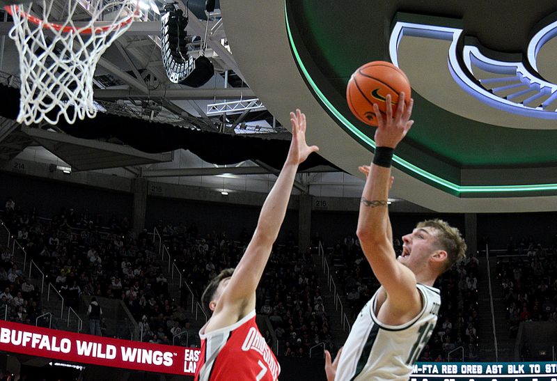 Feb 22, 2026; East Lansing, Michigan, USA;  Michigan State Spartans center Carson Cooper (15) shoots over Ohio State Buckeyes center Ivan Njegovan (7) during the second half at Jack Breslin Student Events Center. Mandatory Credit: Dale Young-Imagn Images