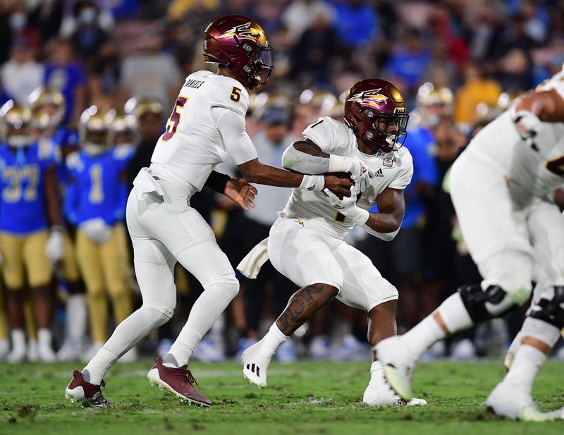 Oct 2, 2021; Pasadena, California, USA; Arizona State Sun Devils quarterback Jayden Daniels (5) hands off to running back DeaMonte Trayanum (1) against the UCLA Bruins during the first half at Rose Bowl. Mandatory Credit: Gary A. Vasquez-USA TODAY Sports