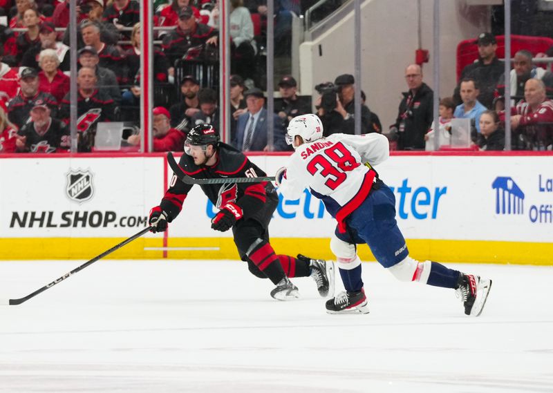 May 10, 2025; Raleigh, North Carolina, USA; Washington Capitals defenseman Rasmus Sandin (38) gets the shot away against Carolina Hurricanes left wing Eric Robinson (50) during the first period in game three of the second round of the 2025 Stanley Cup Playoffs at Lenovo Center. Mandatory Credit: James Guillory-Imagn Images