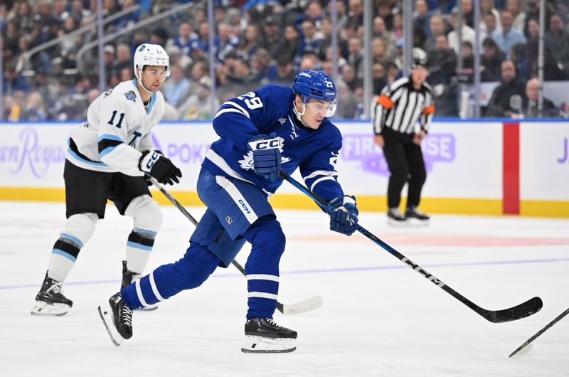 Nov 24, 2024; Toronto, Ontario, CAN;  Toronto Maple Leafs forward Pontus Holmberg (29) shoots the puck as Utah Hockey Club forward Dylan Guenther (11) trails the play in the third period at Scotiabank Arena. Mandatory Credit: Dan Hamilton-Imagn Images