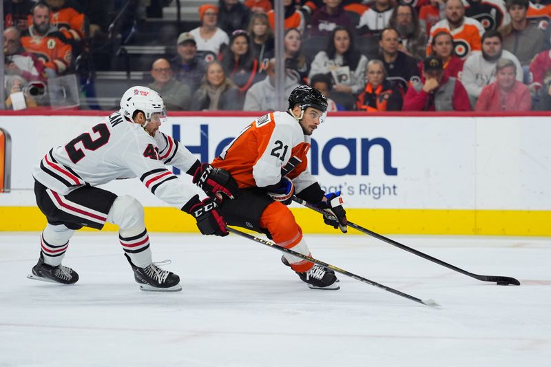 Nov 23, 2024; Philadelphia, Pennsylvania, USA; Philadelphia Flyers center Scott Laughton (21) pushes the puck past Chicago Blackhawks defenseman Nolan Allan (42) in the first period at Wells Fargo Center. Mandatory Credit: Kyle Ross-Imagn Images