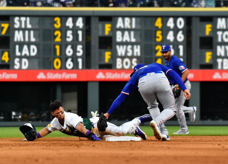 May 11, 2024; Denver, Colorado, USA; Texas Rangers shortstop Corey Seager (5) tags out Colorado Rockies shortstop Ezequiel Tovar (14) on a stolen base attempt in the fifth inning at Coors Field. Mandatory Credit: John Leyba-USA TODAY Sports