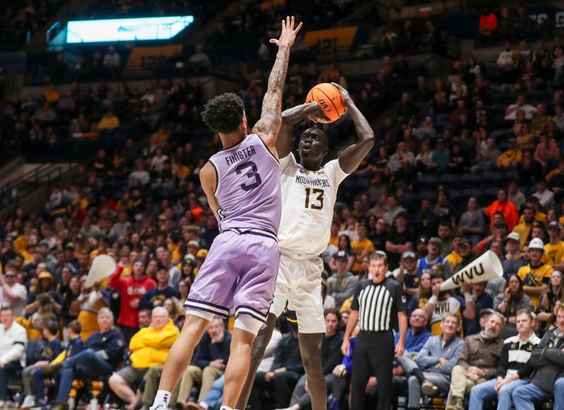 Jan 9, 2024; Morgantown, West Virginia, USA; West Virginia Mountaineers forward Akok Akok (13) shoots a jumper over Kansas State Wildcats guard Dorian Finister (3) during the second half at WVU Coliseum. Mandatory Credit: Ben Queen-USA TODAY Sports