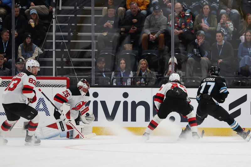 Dec 19, 2025; Salt Lake City, Utah, USA; New Jersey Devils goaltender Jacob Markstrom (25) blocks a shot by Utah Mammoth right wing JJ Peterka (77) during the first period at Delta Center. Mandatory Credit: Rob Gray-Imagn Images