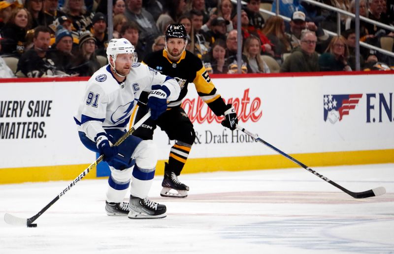 Apr 6, 2024; Pittsburgh, Pennsylvania, USA;  Tampa Bay Lightning center Steven Stamkos (91) handles the puck ahead of Pittsburgh Penguins center Emil Bemstrom (52) during the second period at PPG Paints Arena. The Penguins won 5-4. Mandatory Credit: Charles LeClaire-USA TODAY Sports