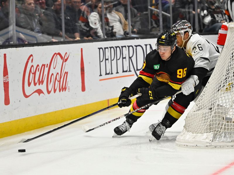 Apr 10, 2023; Los Angeles, California, USA;  Vancouver Canucks defenseman Christian Wolanin (86) is pressured by Los Angeles Kings defenseman Sean Walker (26) as he skates around the net in the first period at Crypto.com Arena. Mandatory Credit: Jayne Kamin-Oncea-USA TODAY Sports