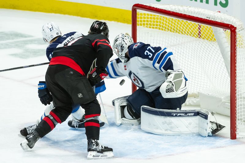 Feb 26, 2025; Ottawa, Ontario, CAN; Winnipeg Jets goalie Connor Hellebuyck (37) makes a save on a shot from  Ottawa Senators center Ridly Greig (71) in the third period at the Canadian Tire Centre. Mandatory Credit: Marc DesRosiers-Imagn Images