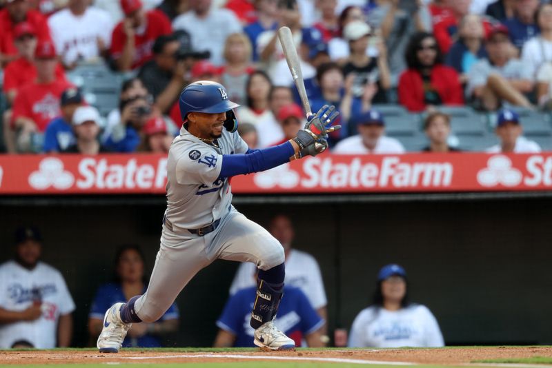 Aug 13, 2025; Anaheim, California, USA;  Los Angeles Dodgers shortstop Mookie Betts (50) hits an RBI single during the first inning against the Los Angeles Angels at Angel Stadium. Mandatory Credit: Kiyoshi Mio-Imagn Images