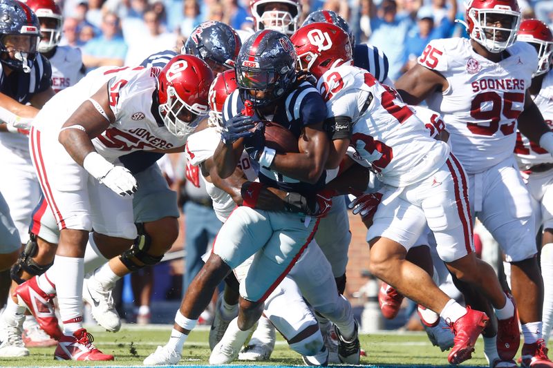 Oct 26, 2024; Oxford, Mississippi, USA; Mississippi Rebels running back Henry Parrish Jr. (21) runs the ball for a touchdown as Oklahoma Sooners linebacker Dasan McCullough (1) and defensive back Eli Bowen (23) attempt to make the tackle during the first half at Vaught-Hemingway Stadium. Mandatory Credit: Petre Thomas-Imagn Images