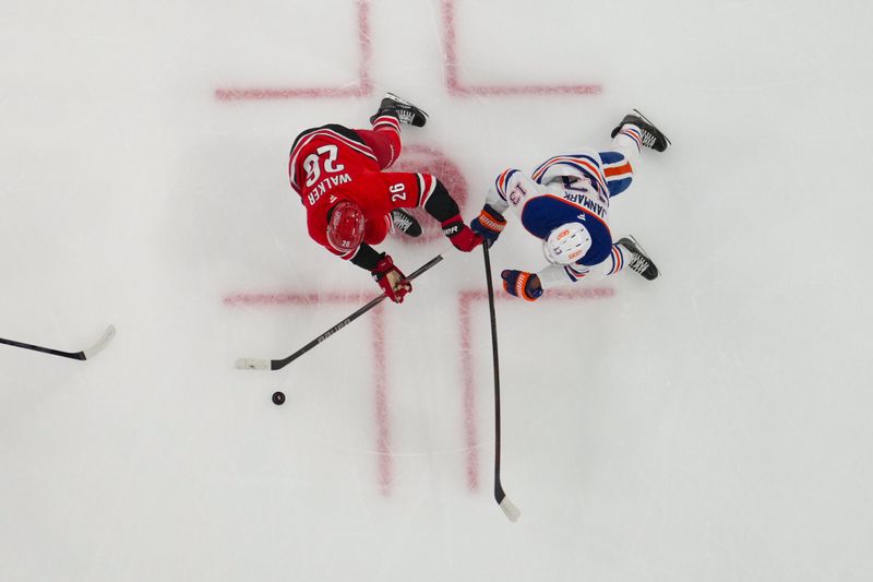 Nov 15, 2025; Raleigh, North Carolina, USA;  Carolina Hurricanes defenseman Sean Walker (26) and Edmonton Oilers center Mattias Janmark (13) battle over the puck during the first period at Lenovo Center. Mandatory Credit: James Guillory-Imagn Images