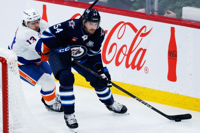 Jan 13, 2026; Winnipeg, Manitoba, CAN; Winnipeg Jets defenseman Dylan Samberg (54) skates against New York Islanders forward Mathew Barzal (13) during the third period at Canada Life Centre. Mandatory Credit: Terrence Lee-Imagn Images