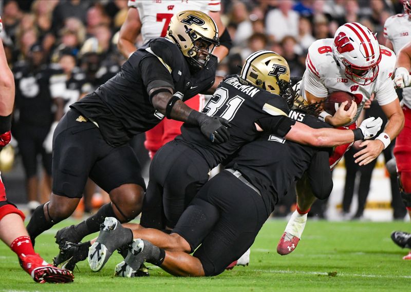 Sep 22, 2023; West Lafayette, Indiana, USA; Purdue Boilermakers defensive back Dillon Thieneman (31) and Purdue Boilermakers outside linebacker Kydran Jenkins (4) tackle Wisconsin Badgers quarterback Tanner Mordecai (8) during the first half at Ross-Ade Stadium. Mandatory Credit: Robert Goddin-USA TODAY Sports