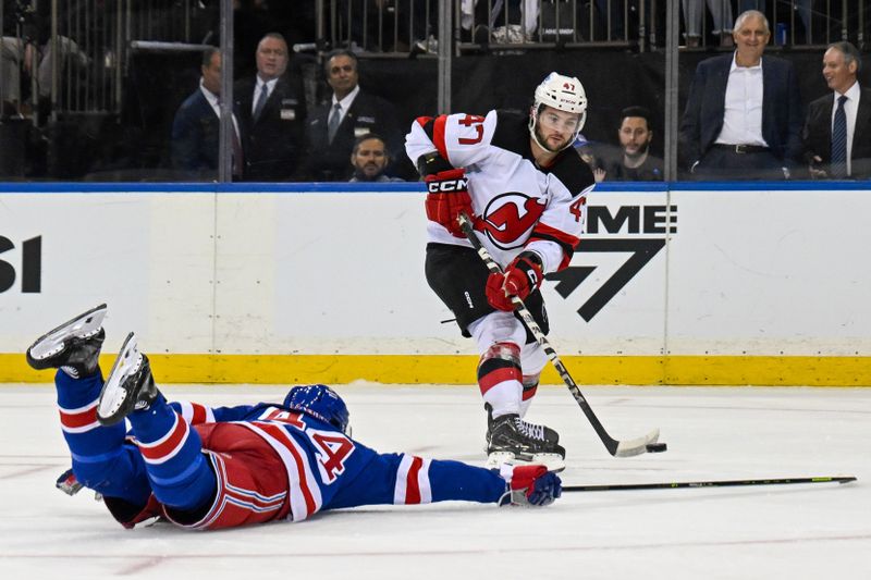 Oct 2, 2025; New York, New York, USA;  New Jersey Devils left wing Paul Cotter (47) attempts a shot defended by New York Rangers defenseman Vladislav Gavrikov (44) during the third period at Madison Square Garden. Mandatory Credit: Dennis Schneidler-Imagn Images