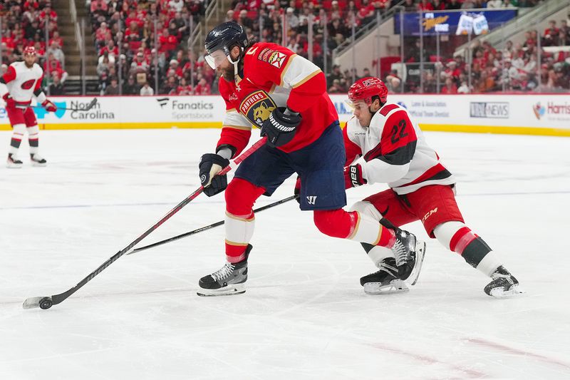 Dec 23, 2025; Raleigh, North Carolina, USA;  Florida Panthers defenseman Aaron Ekblad (5) skates with the puck against Carolina Hurricanes center Logan Stankoven (22) during the first period at Lenovo Center. Mandatory Credit: James Guillory-Imagn Images