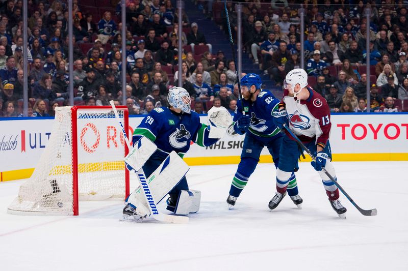 Mar 13, 2024; Vancouver, British Columbia, CAN; As Colorado Avalanche forward Valeri Nichushkin (13) battles with Vancouver Canucks defenseman Ian Cole (82) the game winning shot from forward Nathan MacKinnon (29) beats goalie Casey DeSmith (29) in overtime at Rogers Arena. Colorado won 4 -3 in overtime. Mandatory Credit: Bob Frid-USA TODAY Sports