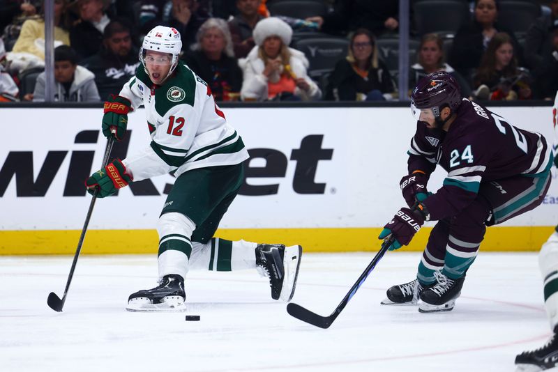 Mar 19, 2024; Anaheim, California, USA; Minnesota Wild left wing Matt Boldy (12) passes the puck against Anaheim Ducks center Bo Groulx (24) during the third period of a game at Honda Center. Mandatory Credit: Jessica Alcheh-USA TODAY Sports