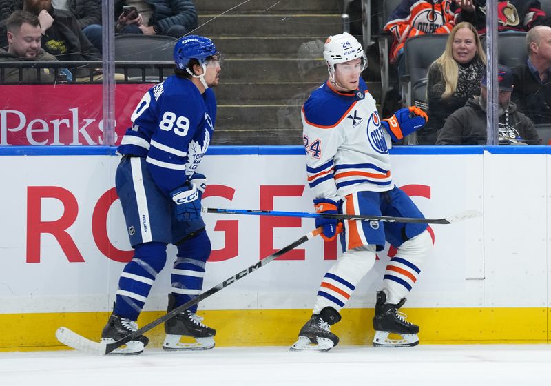 Dec 13, 2025; Toronto, Ontario, CAN; Toronto Maple Leafs left wing Nicholas Robertson (89) battles along the boards with Edmonton Oilers defenceman Spencer Stastney (24) during the third period at Scotiabank Arena. Mandatory Credit: Nick Turchiaro-Imagn Images