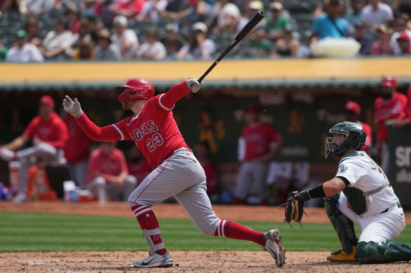 Jul 21, 2024; Oakland, California, USA; Los Angeles Angels first baseman Brandon Drury (23) hits an RBI sacrifice fly against the Oakland Athletics during the fourth inning at Oakland-Alameda County Coliseum. Mandatory Credit: Darren Yamashita-USA TODAY Sports