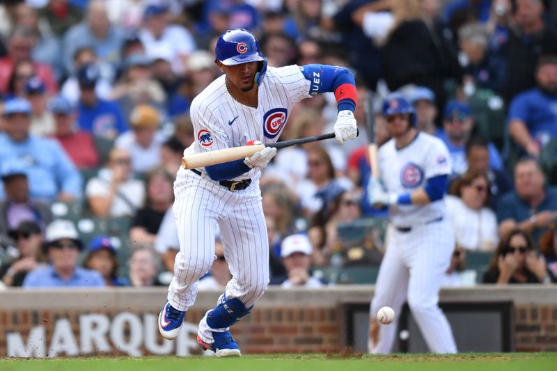 Sep 29, 2024; Chicago, Illinois, USA; Chicago Cubs shortstop Luis Vazquez (12) bunts for his first MLB hit during the seventh inning against the Cincinnati Reds at Wrigley Field. Mandatory Credit: Patrick Gorski-Imagn Images