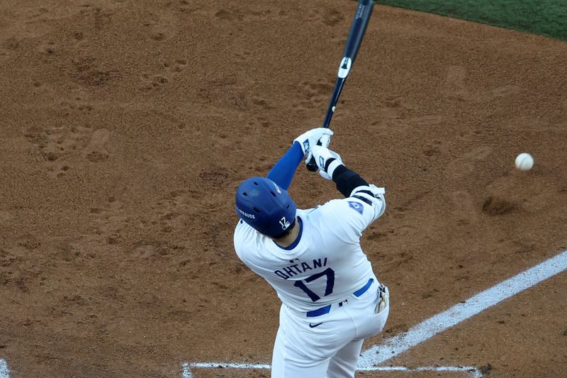 Oct 13, 2024; Los Angeles, California, USA; Los Angeles Dodgers two-way player Shohei Ohtani (17) hits a RBI single against the New York Mets in the second inning during game one of the NLCS for the 2024 MLB Playoffs at Dodger Stadium. Mandatory Credit: Kiyoshi Mio-Imagn Images