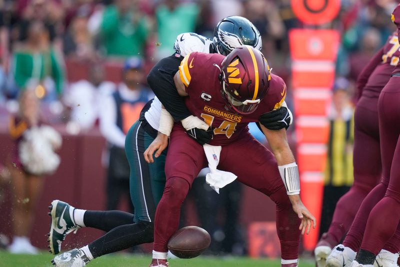 Washington Commanders quarterback Sam Howell (14) drops the ball as he is hit from behind by Philadelphia Eagles linebacker Haason Reddick (7) during the second half of an NFL football game, Sunday, Oct. 29, 2023, in Landover, Md. (AP Photo/Alex Brandon)