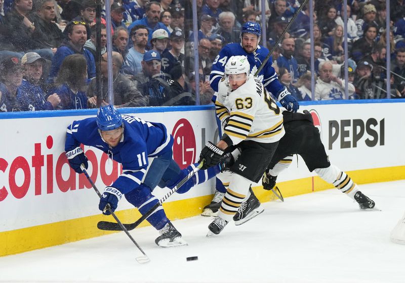 Apr 27, 2024; Toronto, Ontario, CAN; Boston Bruins left wing Brad Marchand (63) battles for the puck with Toronto Maple Leafs center Max Domi (11) during the first period in game four of the first round of the 2024 Stanley Cup Playoffs at Scotiabank Arena. Mandatory Credit: Nick Turchiaro-USA TODAY SportsMandatory Credit: Nick Turchiaro-USA TODAY Sports