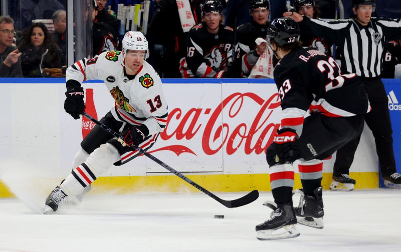 Jan 18, 2024; Buffalo, New York, USA;  Chicago Blackhawks left wing Zach Sanford (13) looks to play the puck as Buffalo Sabres defenseman Ryan Johnson (33) defends during the first period at KeyBank Center. Mandatory Credit: Timothy T. Ludwig-USA TODAY Sports