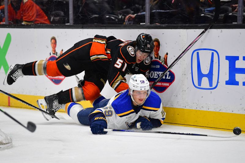 Apr 7, 2024; Anaheim, California, USA; Anaheim Ducks defenseman Olen Zellweger (51) plays for the puck against St. Louis Blues center Nikita Alexandrov (59) during the first period at Honda Center. Mandatory Credit: Gary A. Vasquez-USA TODAY Sports