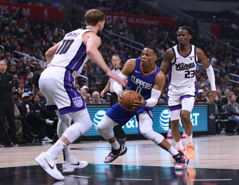 LOS ANGELES, CALIFORNIA - DECEMBER 12: Russell Westbrook #0 of the LA Clippers dribbles between Domantas Sabonis #10 and Keon Ellis #23 of the Sacramento Kings during a 119-99 Clippers win at Crypto.com Arena on December 12, 2023 in Los Angeles, California.  NOTE TO USER: User expressly acknowledges and agrees that, by downloading and or using this photograph, User is consenting to the terms and conditions of the Getty Images License Agreement. (Photo by Harry How/Getty Images)