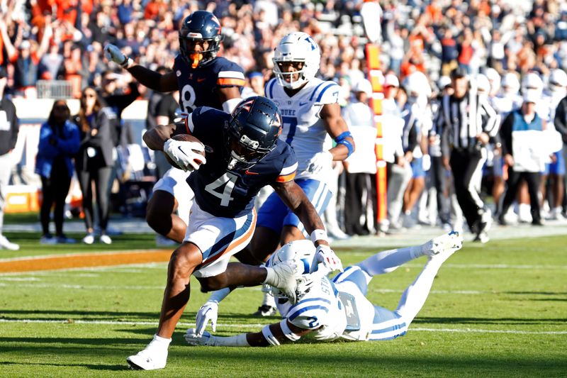 Nov 18, 2023; Charlottesville, Virginia, USA; Virginia Cavaliers wide receiver Malik Washington (4) scores a touchdown as Duke Blue Devils safety Jaylen Stinson (2) chases during the first quarter at Scott Stadium. Mandatory Credit: Geoff Burke-USA TODAY Sports